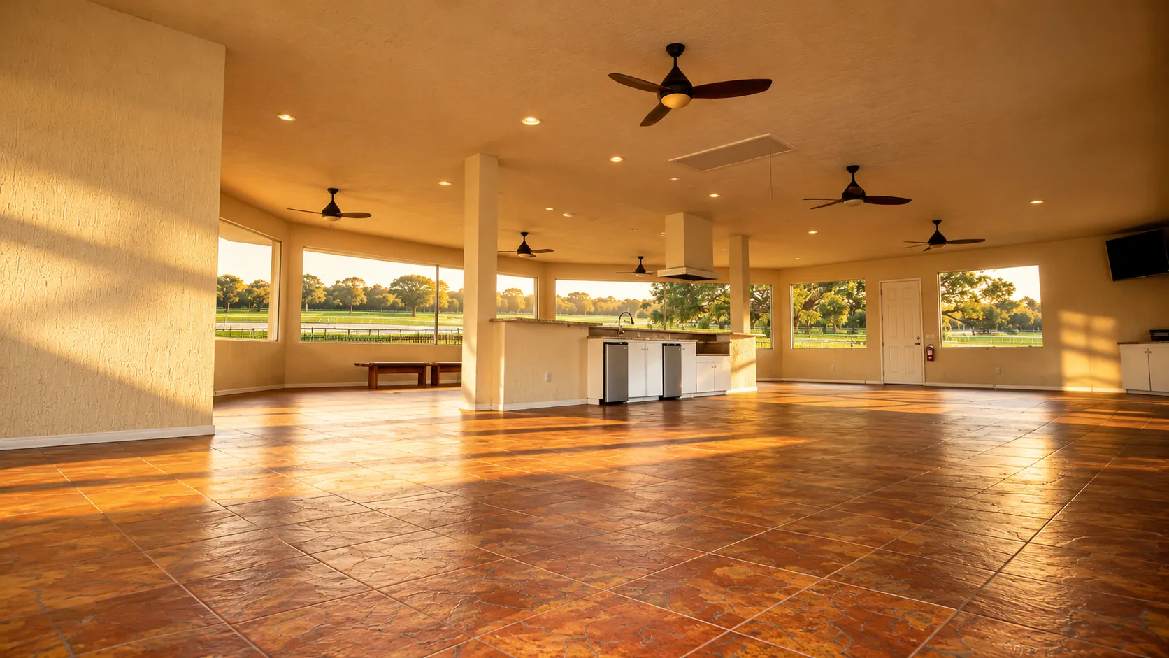 The same hall from another corner, low sunset light raking across the terracotta tile floor past the bar counter and benches