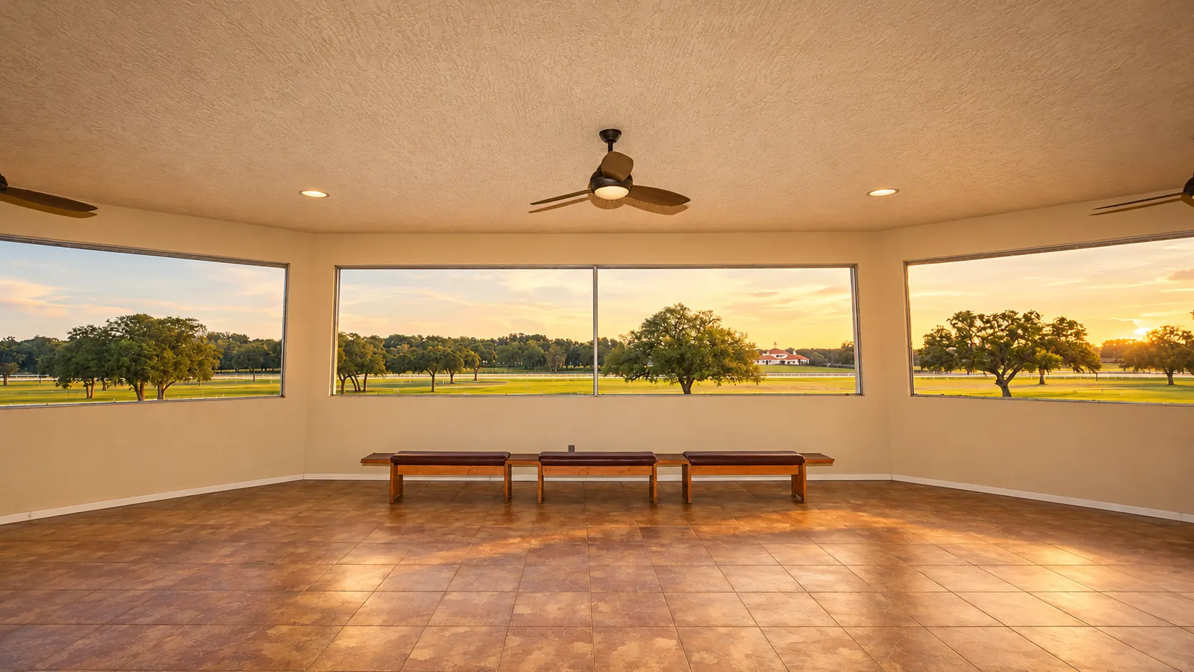 Cushioned window benches arranged beneath a bay of picture windows looking out over the pasture and rail fencing