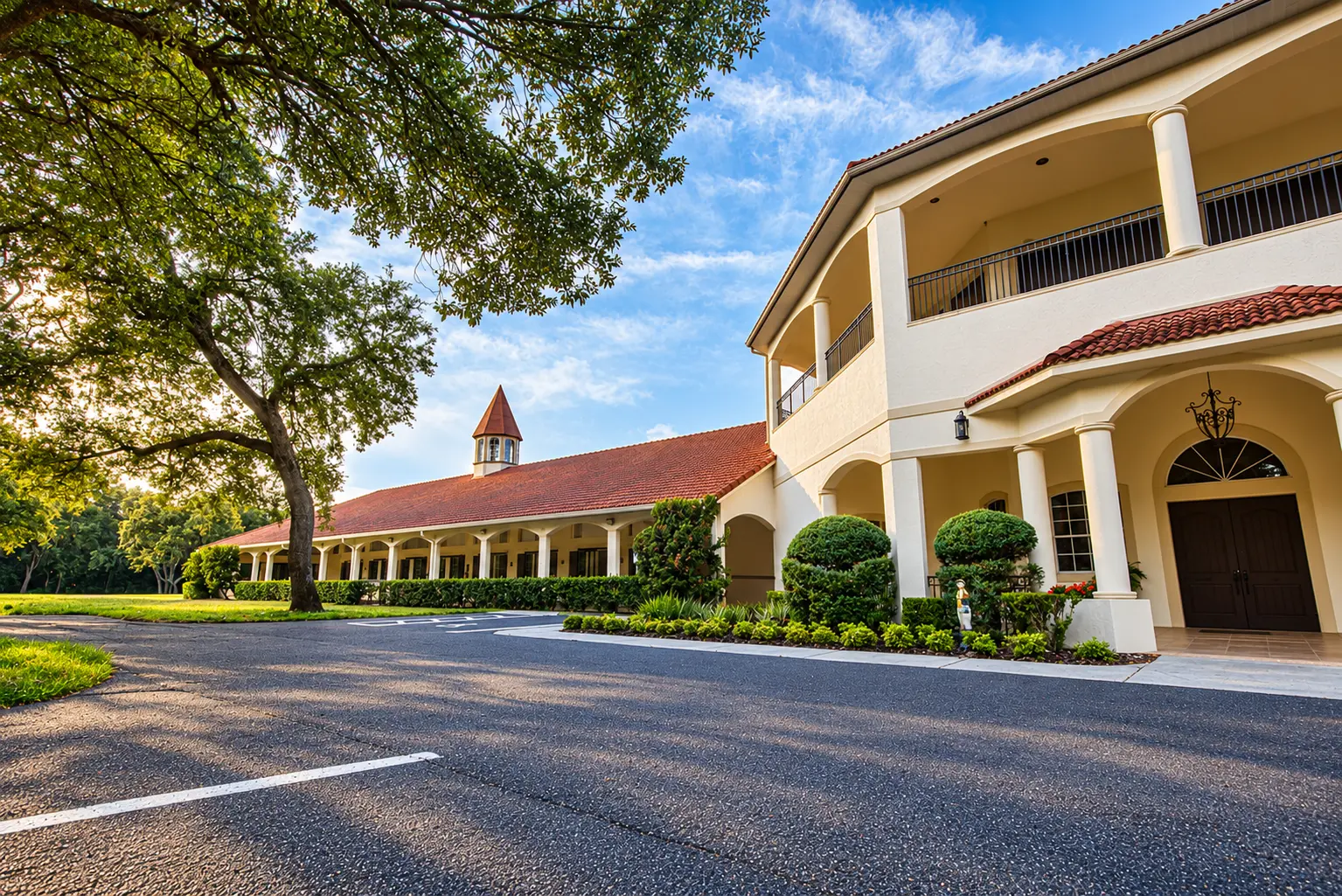 Golden light across the drive — a live oak beside the long barn wing with its cupola