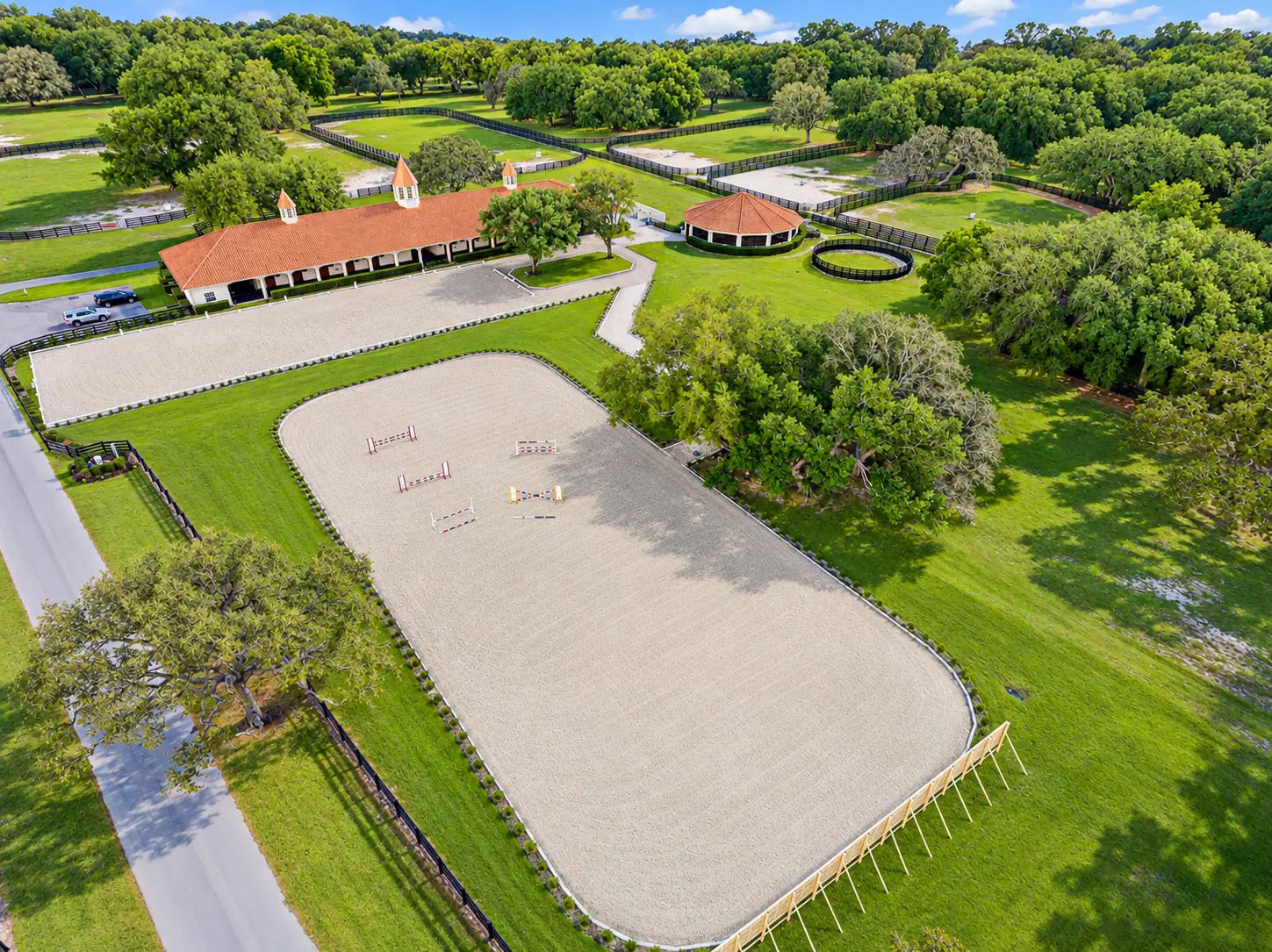 Aerial photo of the GoldMark arena with schooling jumps, the barn complex and paddocks among mature oaks