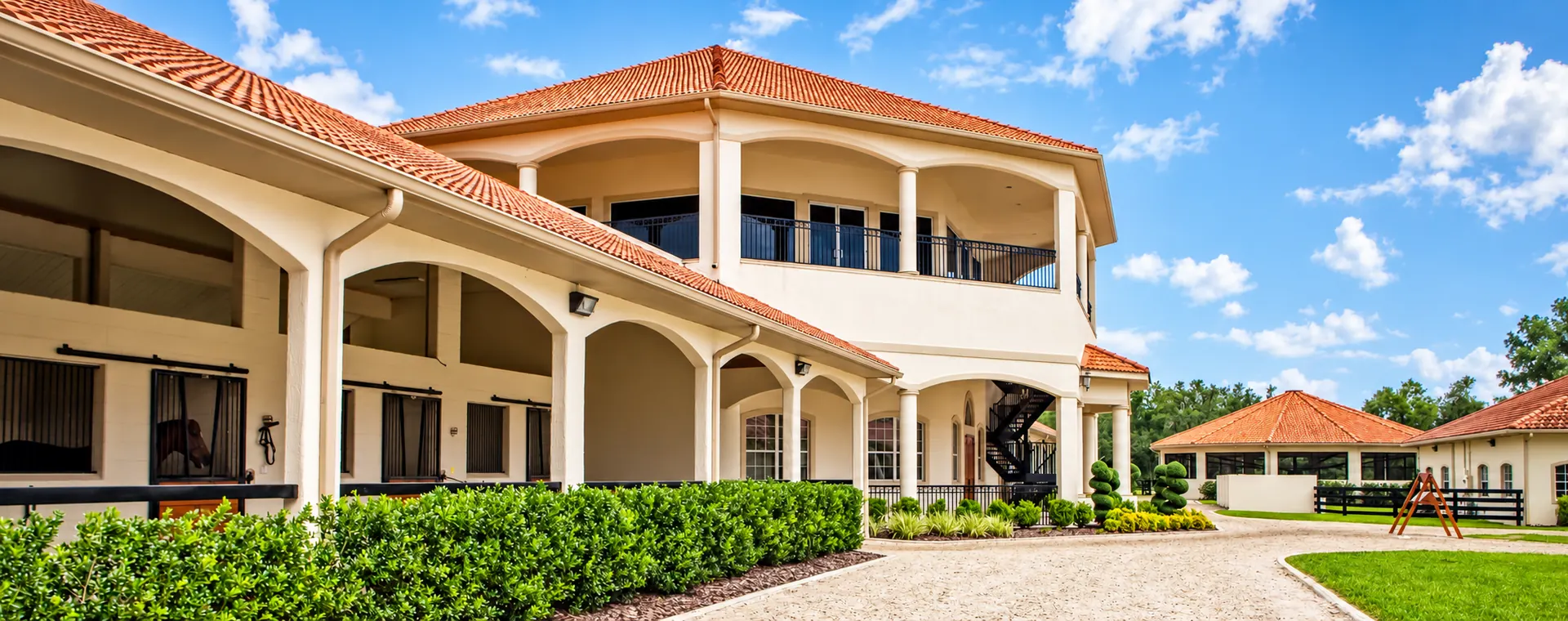 The octagonal main complex in warm light — stalls with a horse at the door, arched colonnade and second-floor balcony
