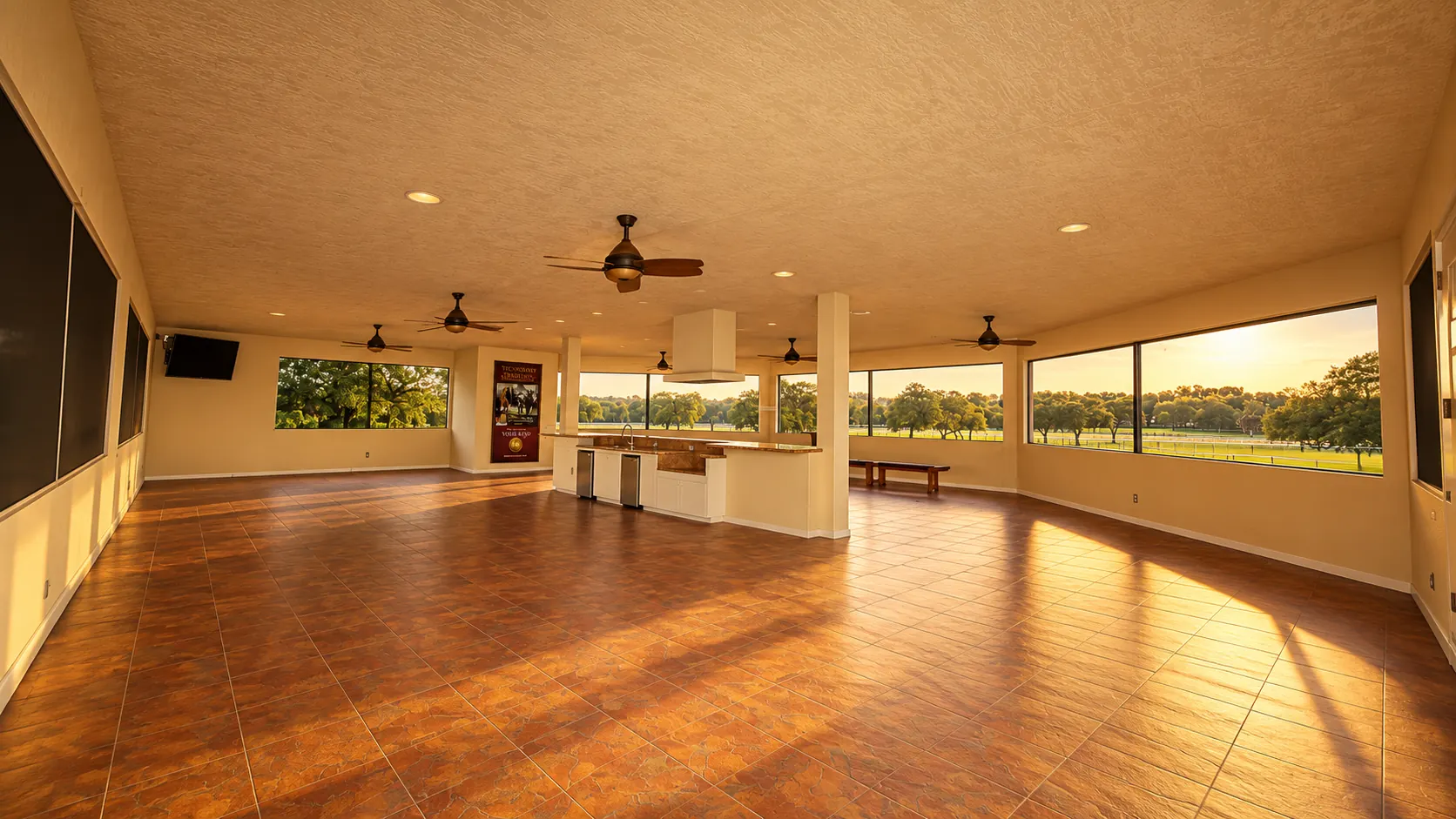 The event hall — a terracotta-tiled room with a granite-topped island bar, ceiling fans and picture windows onto sunlit paddocks